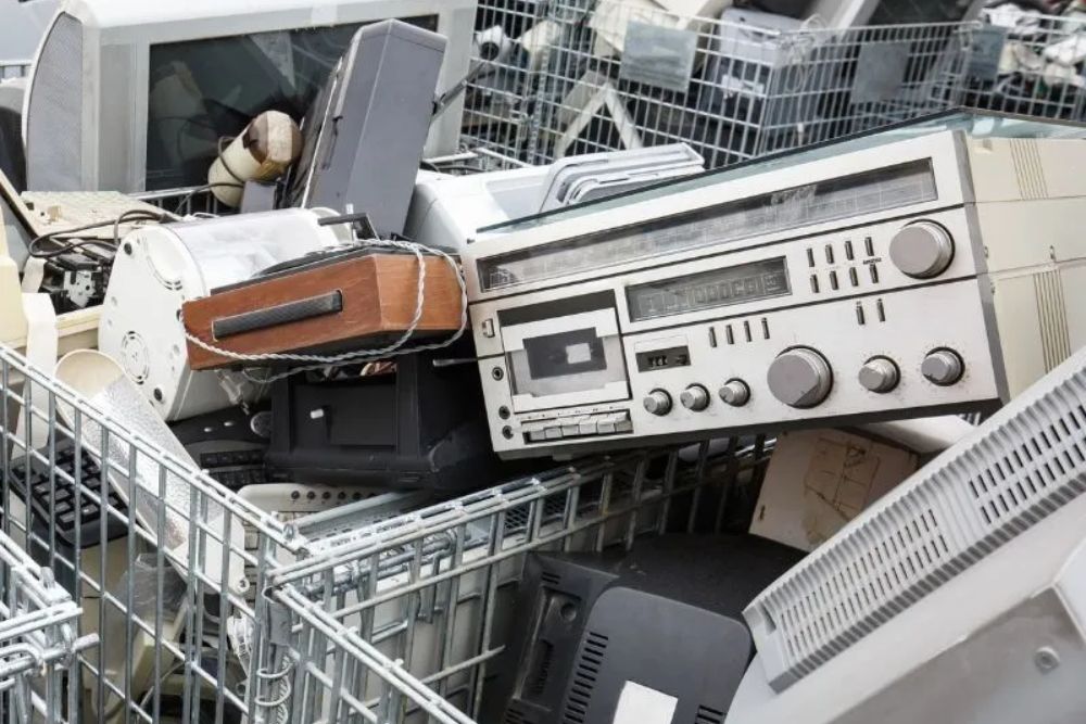 A metal container filled with a pile of electronic waste, representing e-waste junk removal services in Los Angeles, CA.