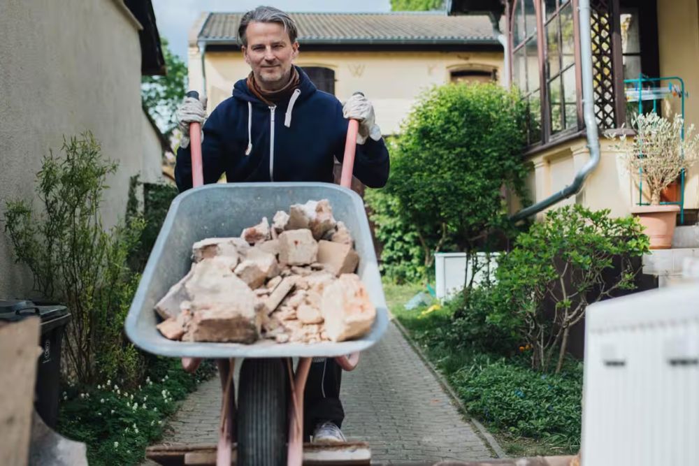 A man is pushing a wheelbarrow full of wood, illustrating an outdoor junk removal service in Los Angeles, CA.